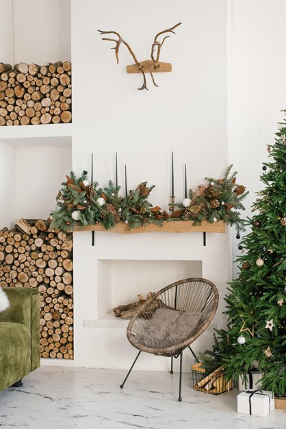 Intérieur de la maison rustique du salon avec un fauteuil en bois de cheminée de guirlande de Noël et des décorations d'arbre de Noël pour la célébration des vacances de Noël