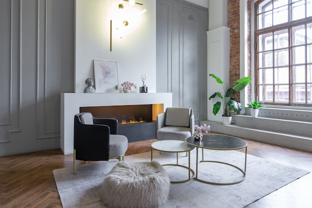 Intérieur minimaliste d'un appartement décloisonné ultra moderne avec des murs blancs et gris avec des meubles rembourrés élégants en relief et gris et d'immenses fenêtres