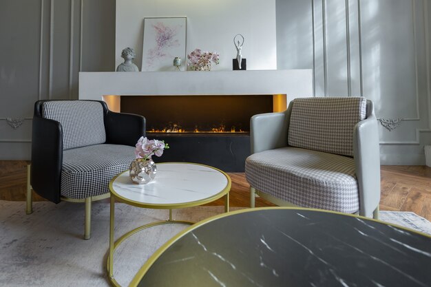 Intérieur minimaliste d'un appartement décloisonné ultra moderne avec des murs blancs et gris avec des meubles rembourrés élégants en relief et gris et d'immenses fenêtres