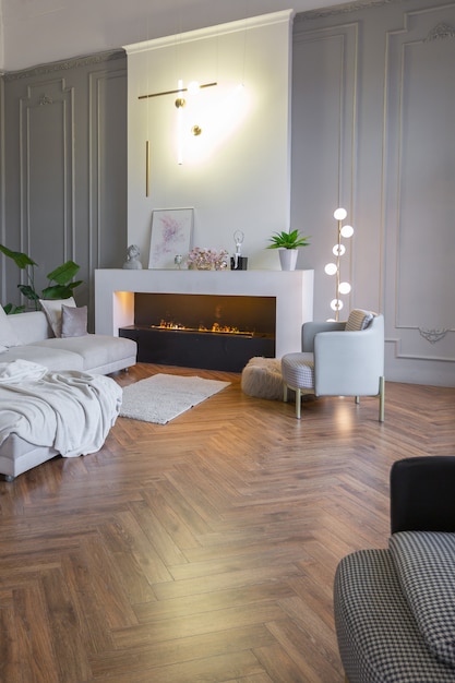 Intérieur minimaliste d'un appartement décloisonné ultra moderne avec des murs blancs et gris avec des meubles rembourrés élégants en relief et gris et d'immenses fenêtres