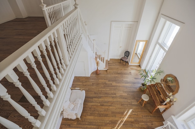 Intérieur moderne d'une chambre lumineuse dans un appartement de deux étages avec des objets de décoration de style balinais avec balcon. murs blancs, parquets et meubles vintage