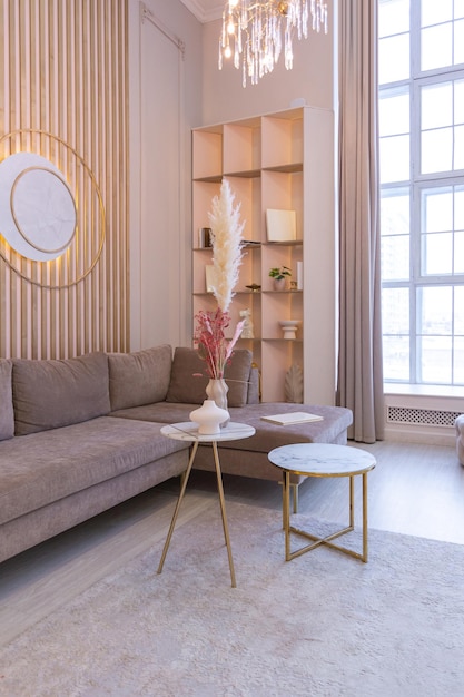 Intérieur moderne luxueux du salon d'un appartement spacieux et lumineux cher. meubles capitonnés et luminaires décoratifs, couleurs pastel douces et ambiance cosy