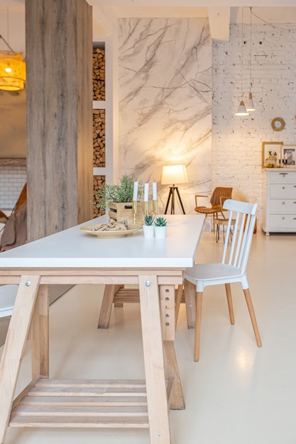 Intérieur Moderne à La Mode D'un Studio Lumineux Avec Des Colonnes En Bois De Style Loft, Décoré De Briques, De Marbre Et De Bois Avec Des Meubles élégants Et Des Murs Blancs