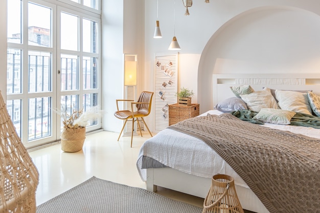 Intérieur moderne à la mode d'un studio lumineux avec des colonnes en bois de style loft, décoré de briques, de marbre et de bois avec des meubles élégants et des murs blancs