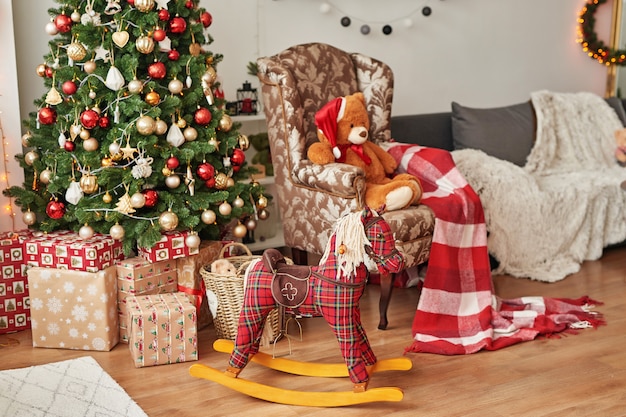 Intérieur de Noël de la chambre des enfantsNoël dans la pépinière. Cheval à bascule et ours en peluche sur fond d'arbre de Noël.