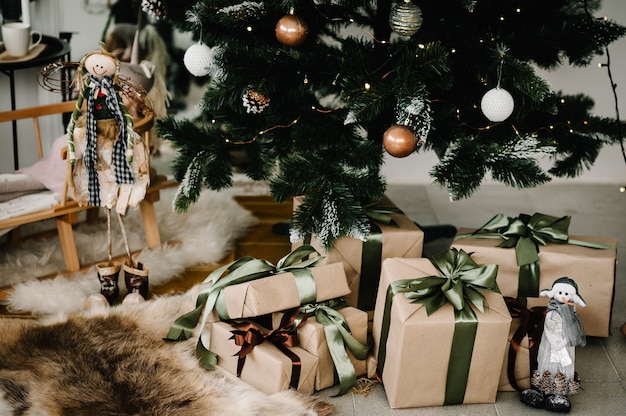 Intérieur de Noël avec sapin dans la chambre. Présente avec un grand arc sur un arbre de Noël de fond. Coffrets cadeaux de luxe pour le nouvel an. Composition de vacances de Noël.