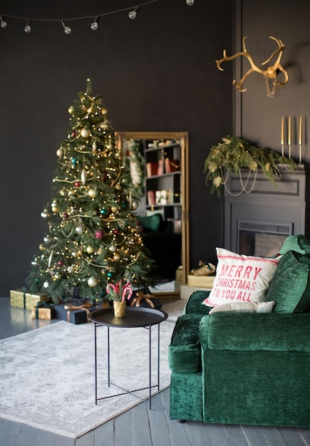 Intérieur de Noël sombre avec cheminée en sapin de Noël et canapé émeraude