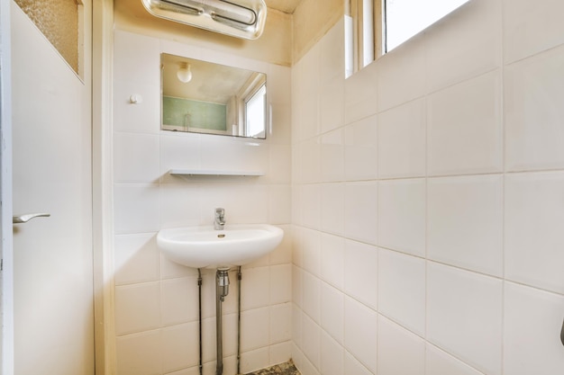 L'intérieur d'une salle de bain à l'ancienne avec des carreaux blancs sur les murs et un évier en céramique dans une maison confortable