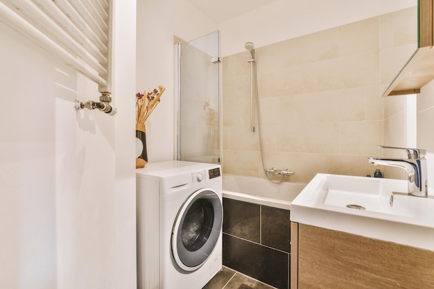 Intérieur de la salle de bain avec baignoire, lave-linge et lavabo en céramique dans une maison spacieuse