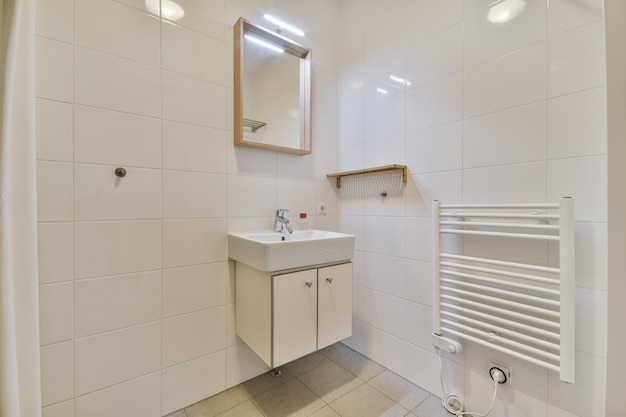 Intérieur de la salle de bain fini avec des carreaux blancs avec un lavabo sous le miroir dans une maison moderne