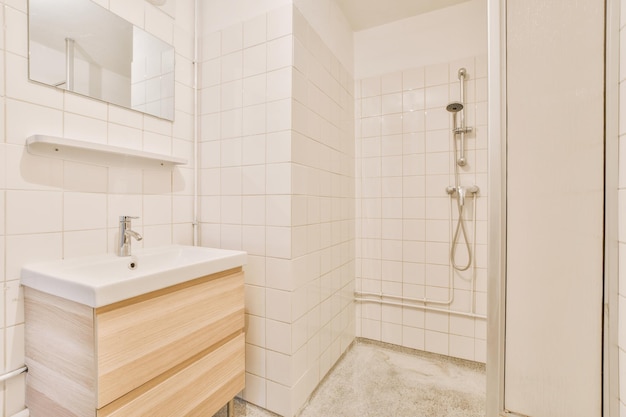 Intérieur de la salle de bain avec lavabo en céramique et système de douche dans une maison confortable