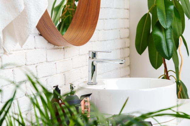 L'intérieur de la salle de bain avec un miroir en forme de cercle dans un cadre en bois et un évier blanc