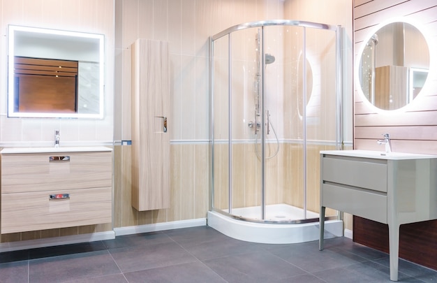 Intérieur de la salle de bain avec murs blancs, cabine de douche avec paroi vitrée, toilettes et lavabo