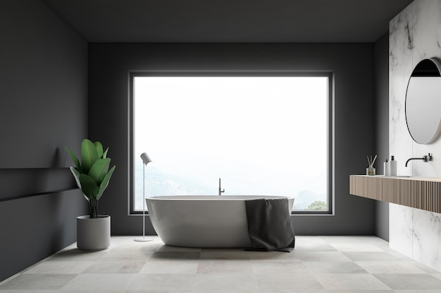 Intérieur de salle de bains de luxe avec murs en marbre gris et blanc, grande fenêtre, carrelage blanc, baignoire blanche et lavabo en bois avec miroir rond. rendu 3d