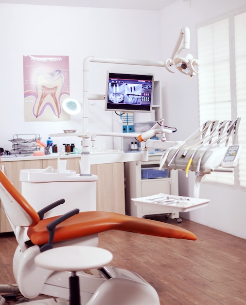 Intérieur de la salle d'opération vide dans la clinique dentaire. Cabinet de stomatologie avec personne dedans et équipement orange pour le traitement oral.