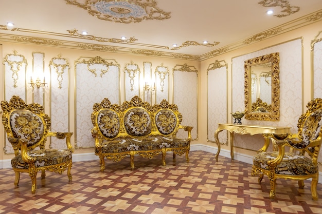 Intérieur de salon luxueux avec de beaux meubles anciens sculptés de couleur or avec des décorations sur les murs dans le style du palais royal