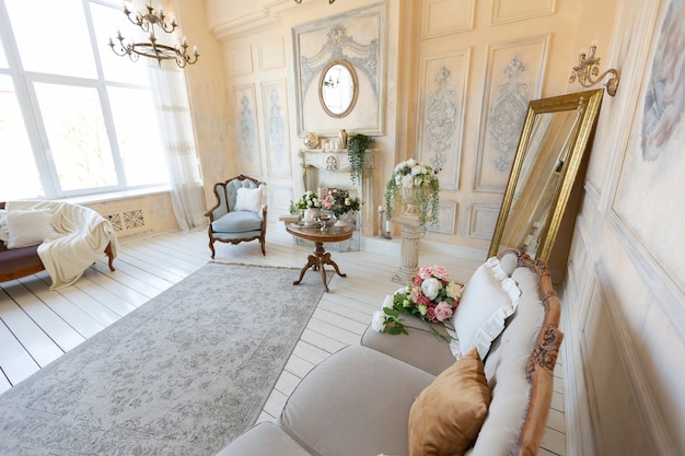Intérieur de salon riche et luxueux de couleur pastel beige avec des meubles anciens et coûteux de style baroque. murs décorés de stuc et de fresques