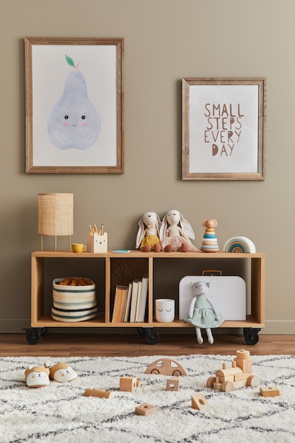 Intérieur scandinave élégant de chambre d'enfant avec jouets, ours en peluche, jouets d'animaux en peluche, meubles, décoration et accessoires pour enfants. Cadres en bois marron sur le mur.