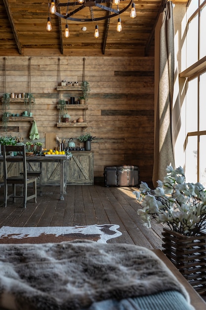 Intérieur sombre et confortable d'une grande maison en bois de campagne, de meubles en bois et de fourrures d'animaux. immense baie vitrée et très haut plafond.