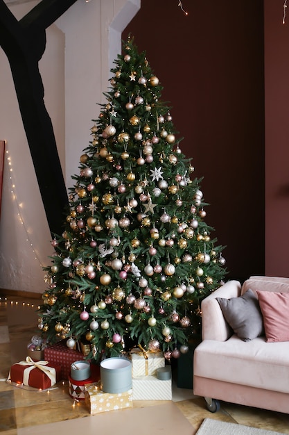 Intérieur sombre de Noël de maison confortable avec arbre de Noël décoré, canapé et cadeaux