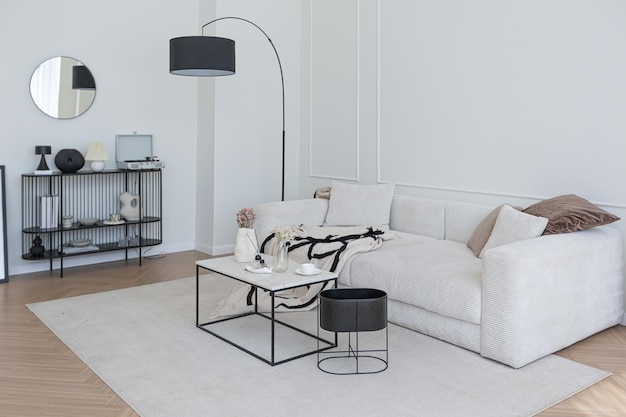 Intérieur super blanc simple, propre et élégant avec un mobilier moderne de couleur nude et des éléments noirs contrastants design de luxe d'un grand salon lumineux