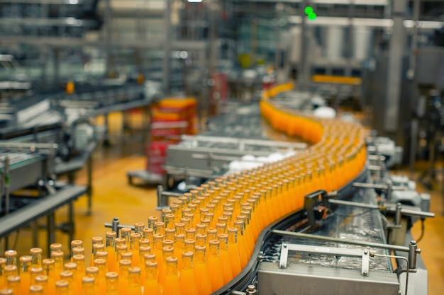 Photo intérieur de l'usine de boissons. convoyeur circulant avec des bouteilles de jus ou d'eau.