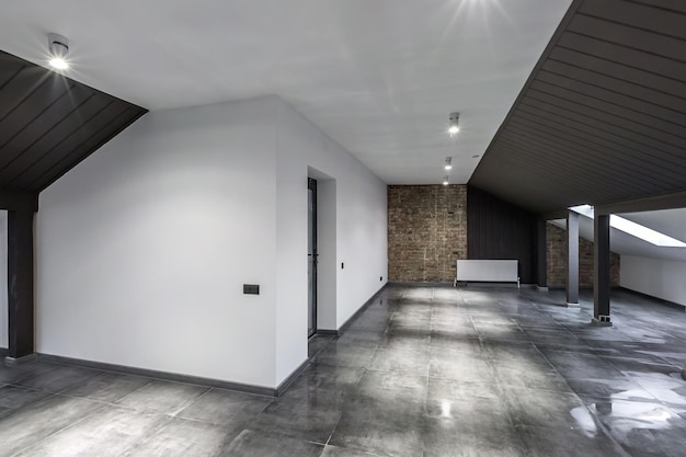 Intérieur vide de la chambre mansardée loft non meublé avec colonnes en bois et sol en béton humide au niveau du toit en couleur de style noir et blanc