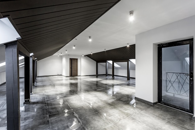 Intérieur vide de la chambre mansardée loft non meublé avec colonnes en bois et sol en béton humide au niveau du toit en couleur de style noir et blanc