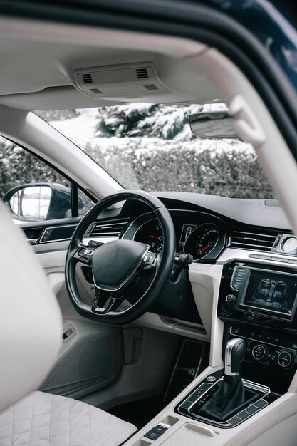 Photo intérieur de voiture moderne, cuir perforé blanc, aluminium, commandes de détails, volant en cuir.