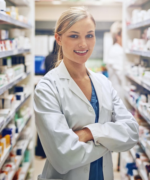 Interne de pharmacie ou portrait de femme avec les bras croisés ou pharmacien dans une clinique de soins de santé ou une pharmacie Sourire fier ou travailleur médical confiant par étagère pour les pilules médicaments ou médicaments pour aider