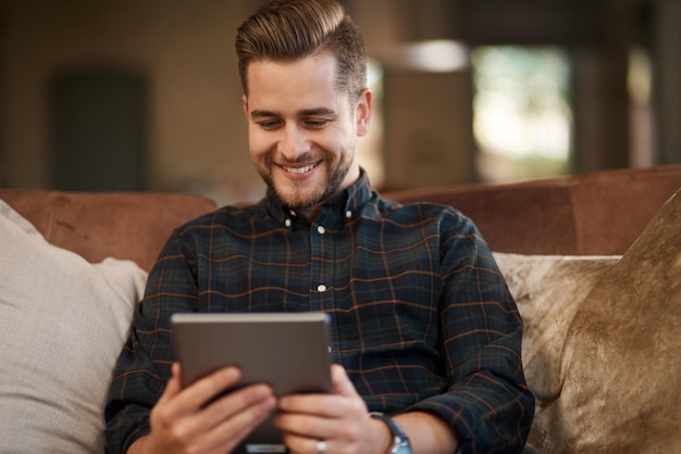 Internet est là pour votre commodité Photo recadrée d'un jeune homme se relaxant sur le canapé à la maison