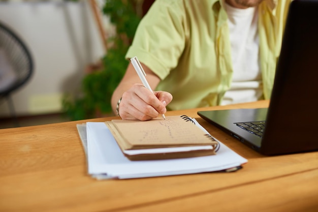 Internet pour l'apprentissage et la recherche d'emploi Main d'homme prenant des notes dans le bloc-notes