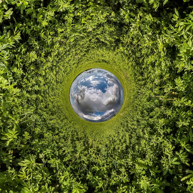 Inversion de la petite planète bleue transformation du panorama sphérique à 360 degrés Vue aérienne abstraite sphérique sur le champ d'herbe verte avec de beaux nuages impressionnants Courbure de l'espace