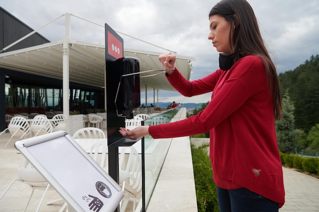 Invités au restaurant Se laver les mains à l'aide d'un désinfectant automatique au gel. Prévention du coronavirus dans un café-restaurant pendant l'épidémie de virus corona et nouveau concept d'épidémie normale