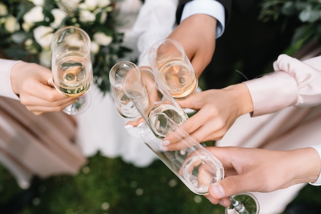 Les invités à un mariage avec les mariés tintent des verres de champagne ou de vin blanc