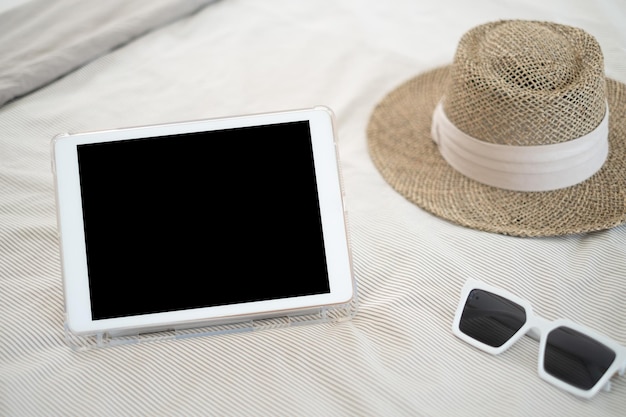 Ipad Verres blancs vides et chapeaux de paille marron sur le lit Concepts de vacances