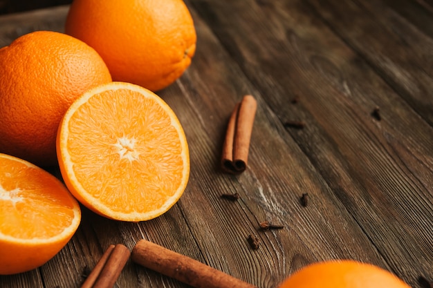 ipe juteuses oranges sur un ancien espace de copie de table en bois. Moitiés d'oranges. Bâtonnets de cannelle