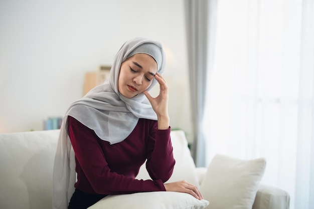 Photo l'islam femme asiatique musulmane portant le hijab déprimée tristement grave ayant une dépression stressante temps triste assise sur le canapé dans le salon à la maison dépression femme triste sérieux concept de santé mentale