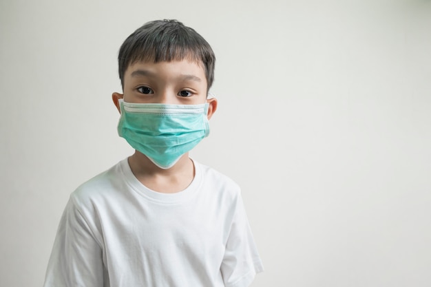 Photo isolé enfant asiatique garçon enfants portant un masque vert couvrant le nez nez bouche, concept de protection contre la maladie du virus corona, les germes et la transmission aérienne