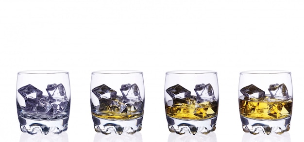 Isoler quatre verres de whisky avec des glaçons sur fond blanc.