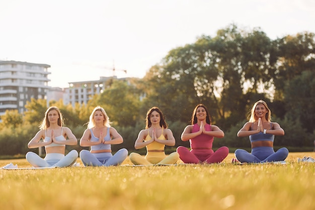 It lotus pose Un groupe de femmes fait du fitness à l'extérieur sur le terrain ensemble