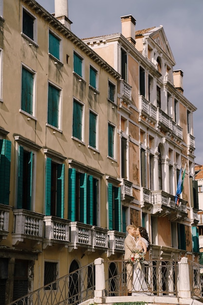 Italie mariage à venise la mariée et le marié se tiennent sur un pont de pierre au-dessus d'un vénitien étroit