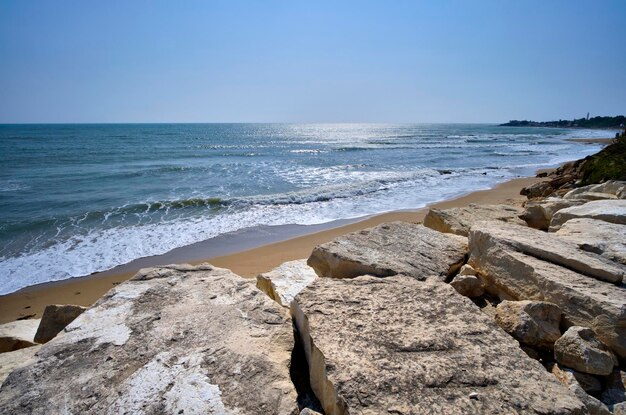 Photo italie, sicile, mer méditerranée, côte sablonneuse du sud-est, pierres brise-lames sur la plage de caucana (province de raguse)