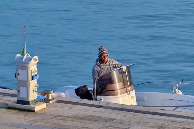 Italie, Sicile, Mer Méditerranée, Marina di Ragusa (Province de Raguse); 4 février 2021, pêcheur en bateau à moteur dans le port - EDITO