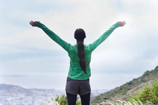 J'ai atteint le sommet Vue arrière d'une jeune femme aventureuse debout les bras tendus sur la montagne