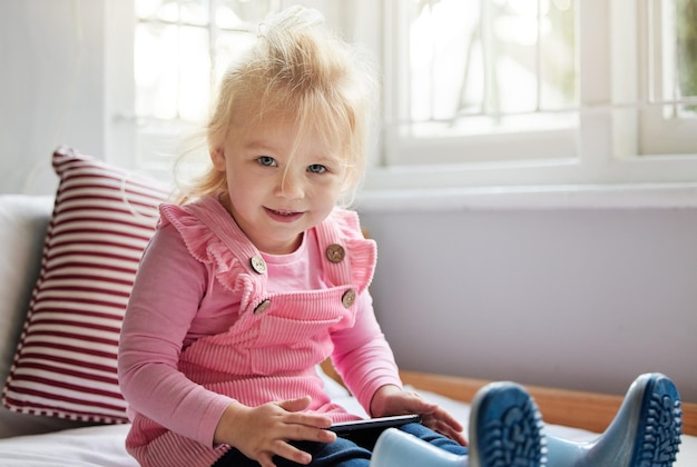 J'ai du temps. Photo d'une petite fille utilisant un téléphone à la maison.