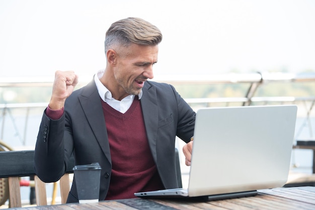 J'ai fait le travail à temps. L'homme heureux vérifie la montre et l'ordinateur portable. Ponctualité. Le gestionnaire fait un geste gagnant. Ponctualité. La ponctualité est l'âme de l'entreprise