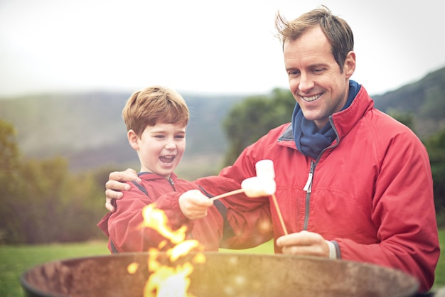 J'ai hâte de les manger Photo d'un père et de son fils faisant rôtir des guimauves sur un feu