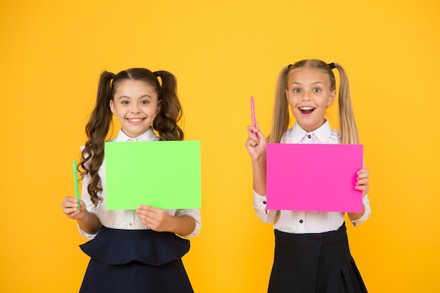 J'ai une idée Petits enfants mignons souriants d'une idée de génie Filles heureuses tenant des feuilles de papier pour écrire une idée sur fond jaune Petits enfants avec du papier vide pour un espace de copie d'idée créative