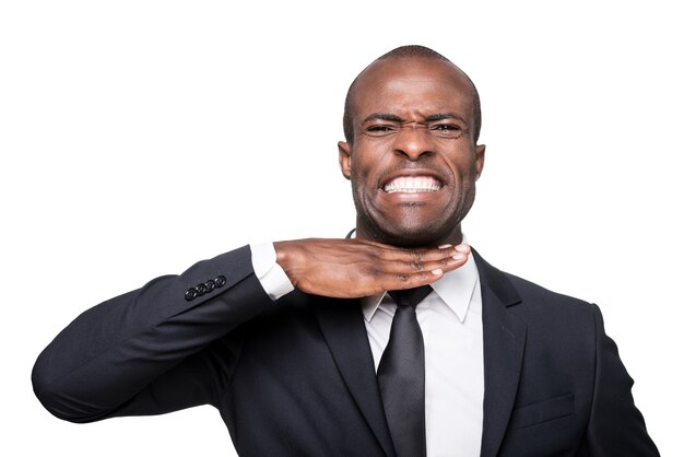 J'en ai marre. Furieux jeune homme africain en tenue de soirée touchant son cou avec la main et grimaçant en se tenant debout isolé sur fond blanc